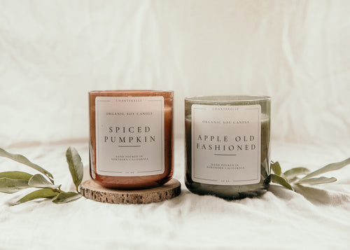 Two candles with labels 'Spiced Pumpkin' and 'Apple Old Fashioned' on a white background.