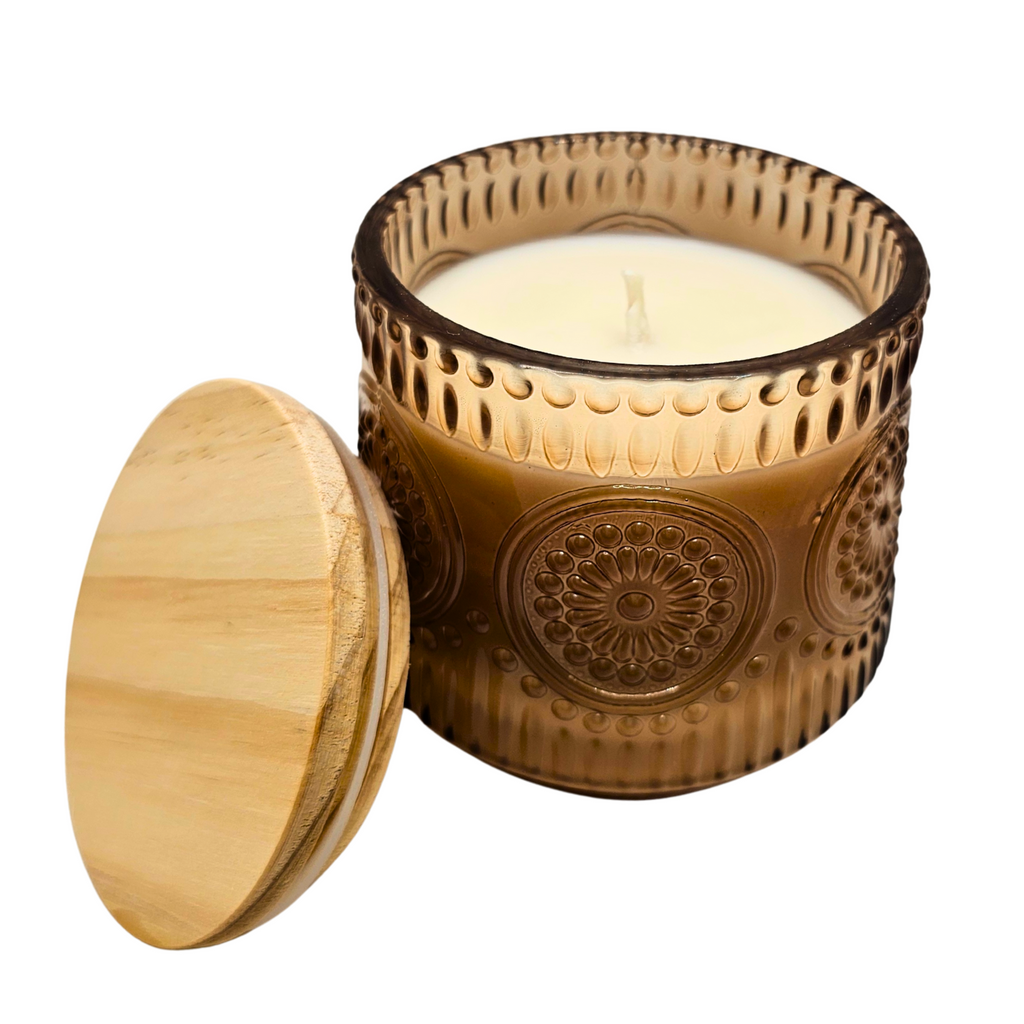 Decorative candle in a brown glass holder with a wooden lid on a white background
