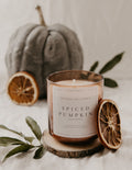 Spiced pumpkin candle with decorative elements on a neutral background